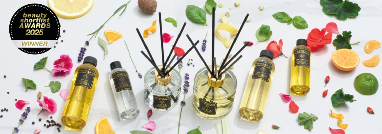 Selection of Imogen's Luxuries Reed Diffusers and Refills presented on a light background and surrounded by natural fruits, flowers, spices and leaves. The image displays the Award winning badge from 2025 Beauty Shortlist Awards
