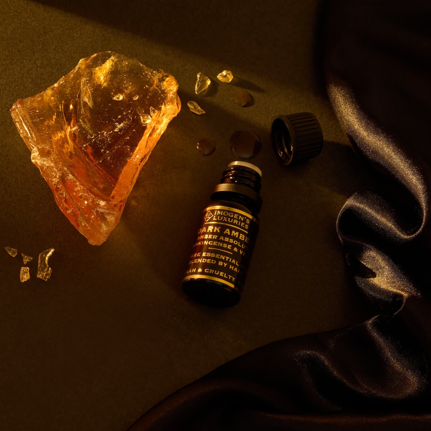 10ml black bottle of Luxury Dark Amber Oud Oil. Blend of Amber Absolute, Vetiver and Frankincense. Bottle is beside Amber Resin. All Natural and alcohol free.