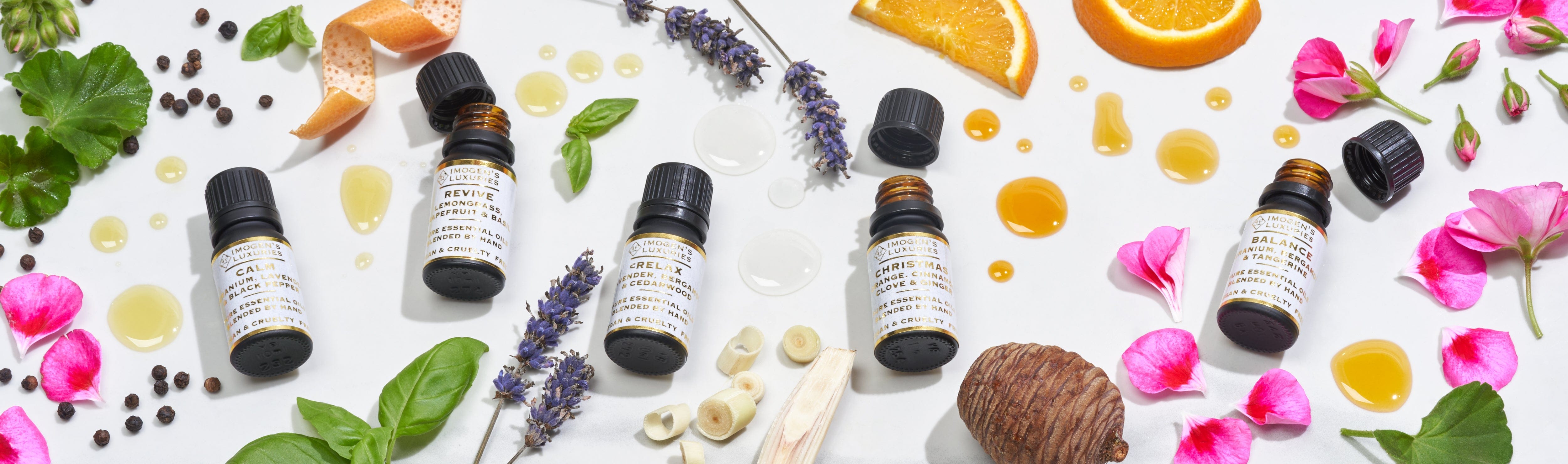 10ml black bottles of award winning pure essential oils. Bottles are surrounded by the natural ingredients in the essential oil blends. Fruits, flowers and leaves surround the bottles.