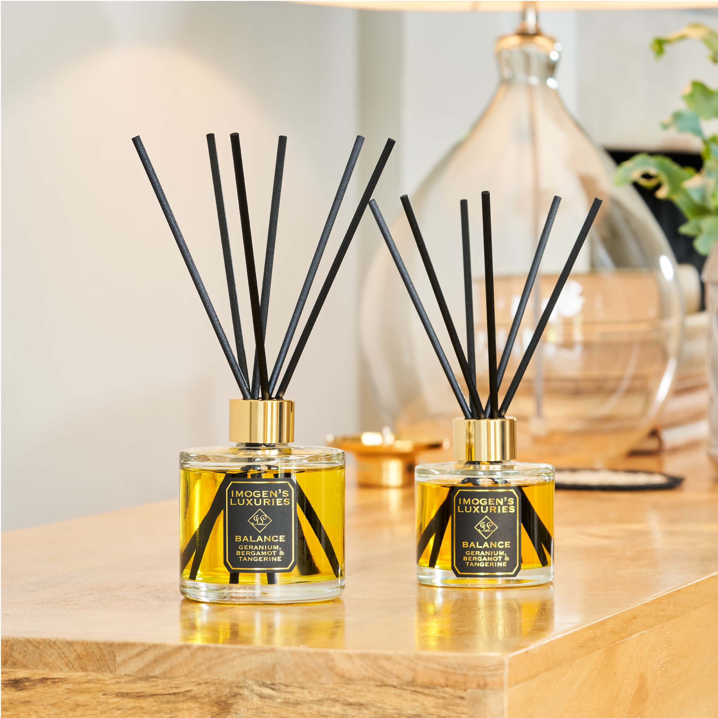 Our 200ml Balance reed diffuser is the larger version of out best selling 100ml diffuser. Scented with our signature fragrance of Geranium, Bergamot & Tangerine Essential Oils. Rich floral Geranium is complimented by the zesty citrus notes of Bergamot with juicy tangerine. Diffuser has thick black reeds and is on a wooden luxury table.