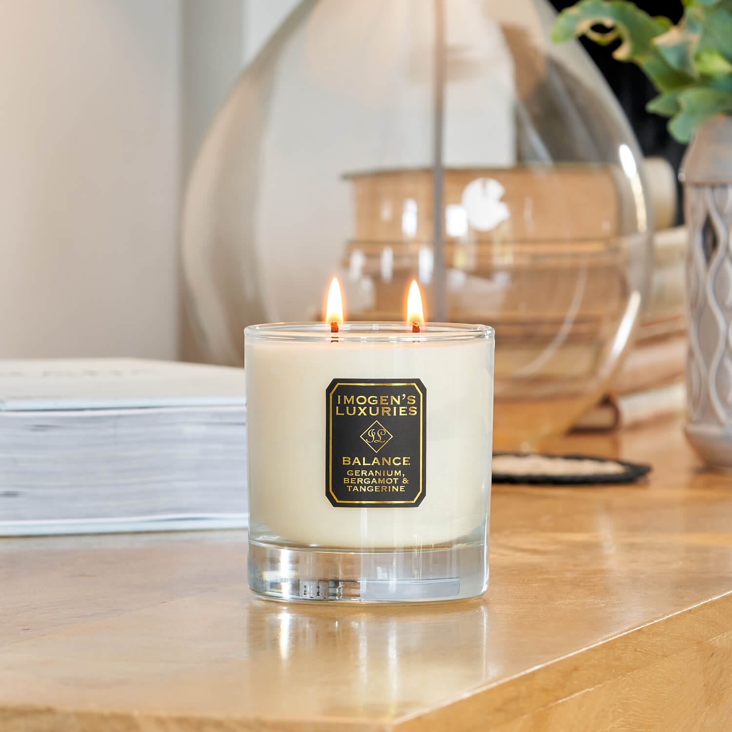 Balance 2 wick glass container candle burning on a luxury wooden sideboard