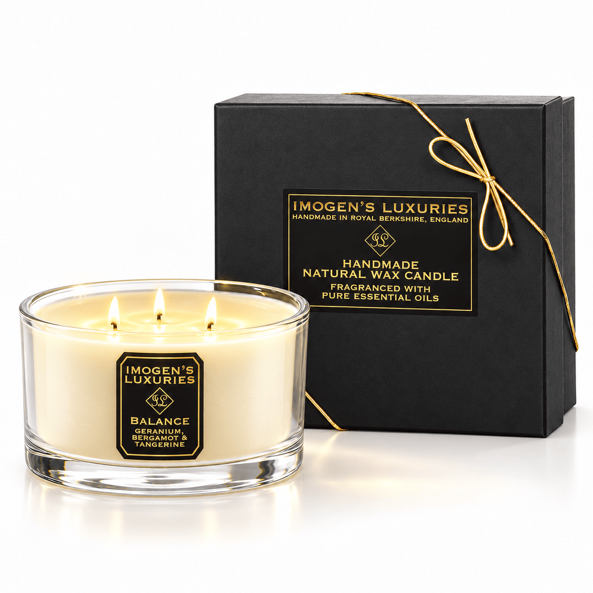 Cream coloured natural wax candle in glass container with 3 wicks, all are lit. Candles is scented with Geranium, Bergamot & Tangerine Essential Oils. On the glass container is a black and gold label saying "Imogen's Luxuries" "Balance". The candle sits by a solid black and gold box with a black and gold label saying "Handmade Natural Wax Candle fragranced with pure essential oils. There is a fine gold bow across the box.