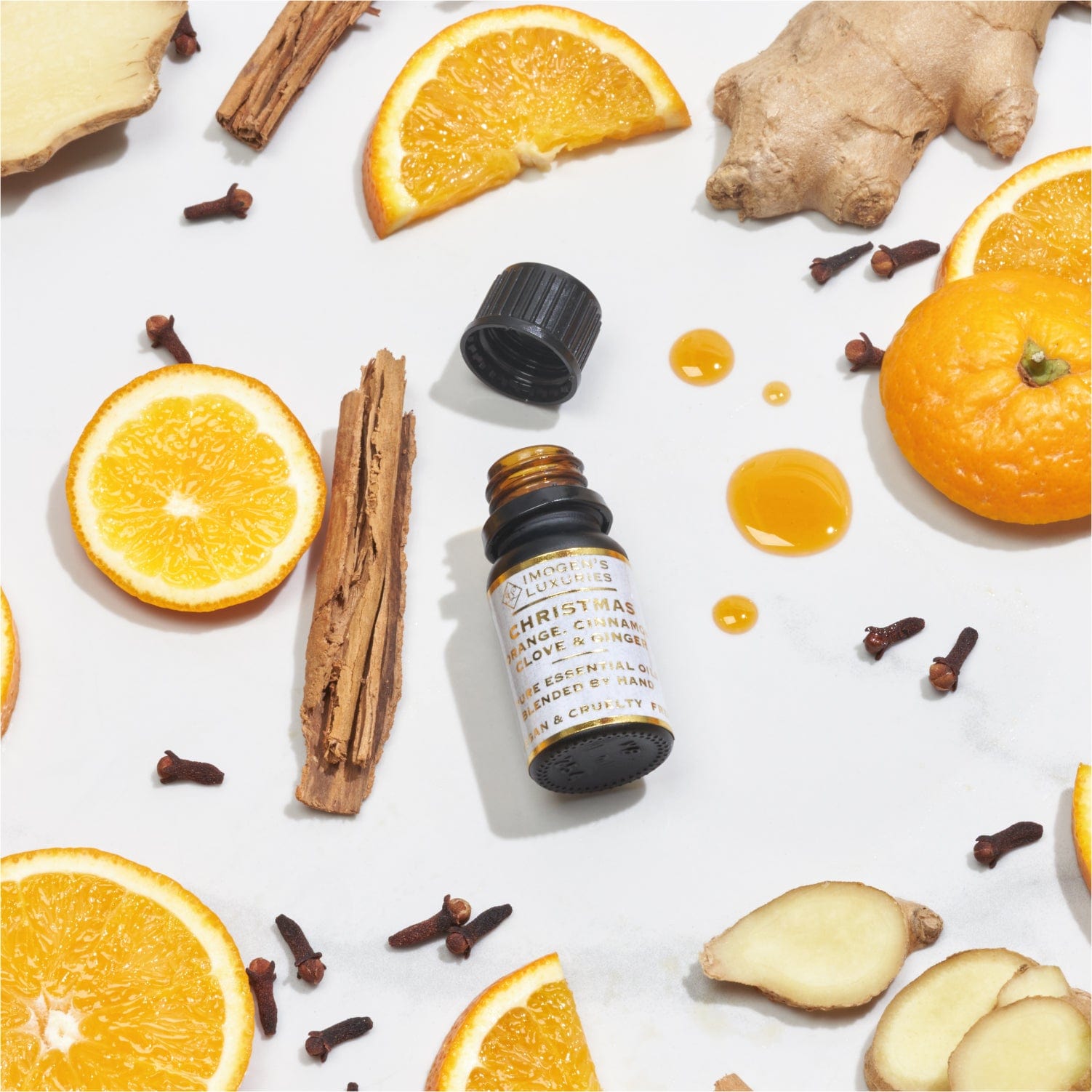 Christmas 10ml award winning concentrated blend of Orange, Cinnamon, Clove and Ginger Essential oils. Black glass bottle with dropper and cap. Surrounded by matching fruit and spice botanicals. Imogen's Luxuries.