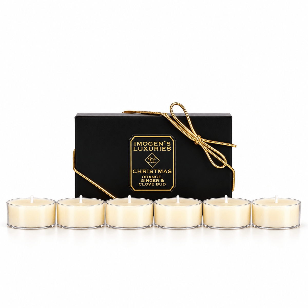 Six cream tea light candles lined up in front of a black gift box with gold lettering and a gold ribbon. The box is labeled 'IMOGEN'S LUXURIES CHRISTMAS" | ORANGE, CINNAMON, CLOVE & GINGER.