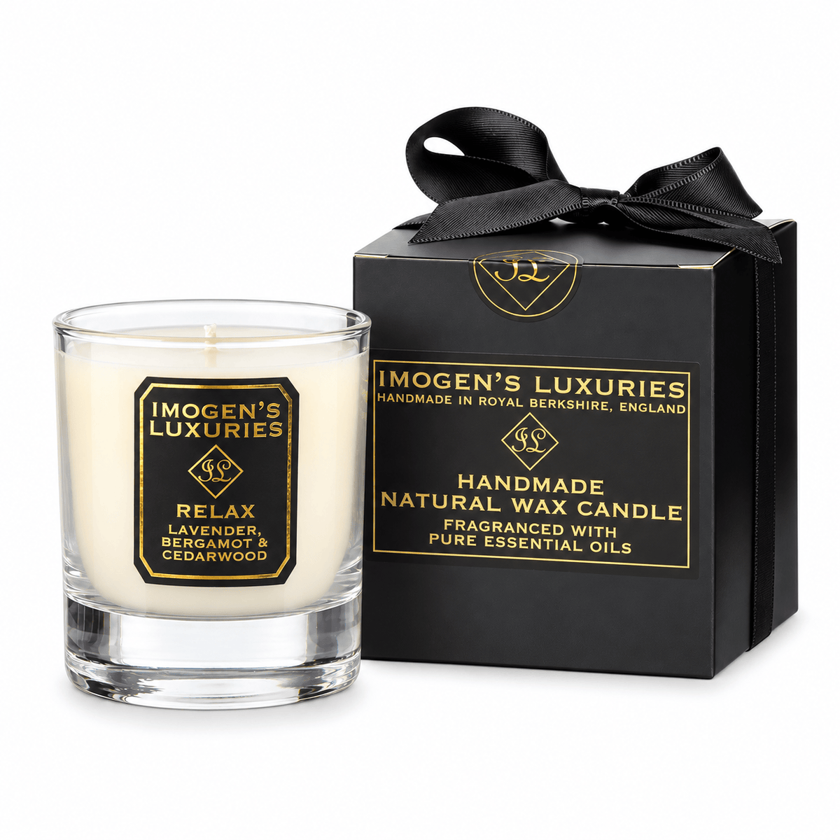 A clear glass candle jar with white wax sits beside a black gift box tied with a black ribbon. Both pieces feature gold branding and text reading Imogen's Luxuries and Relax, with lavender, bergamot, and cedarwood noted on the candle label.