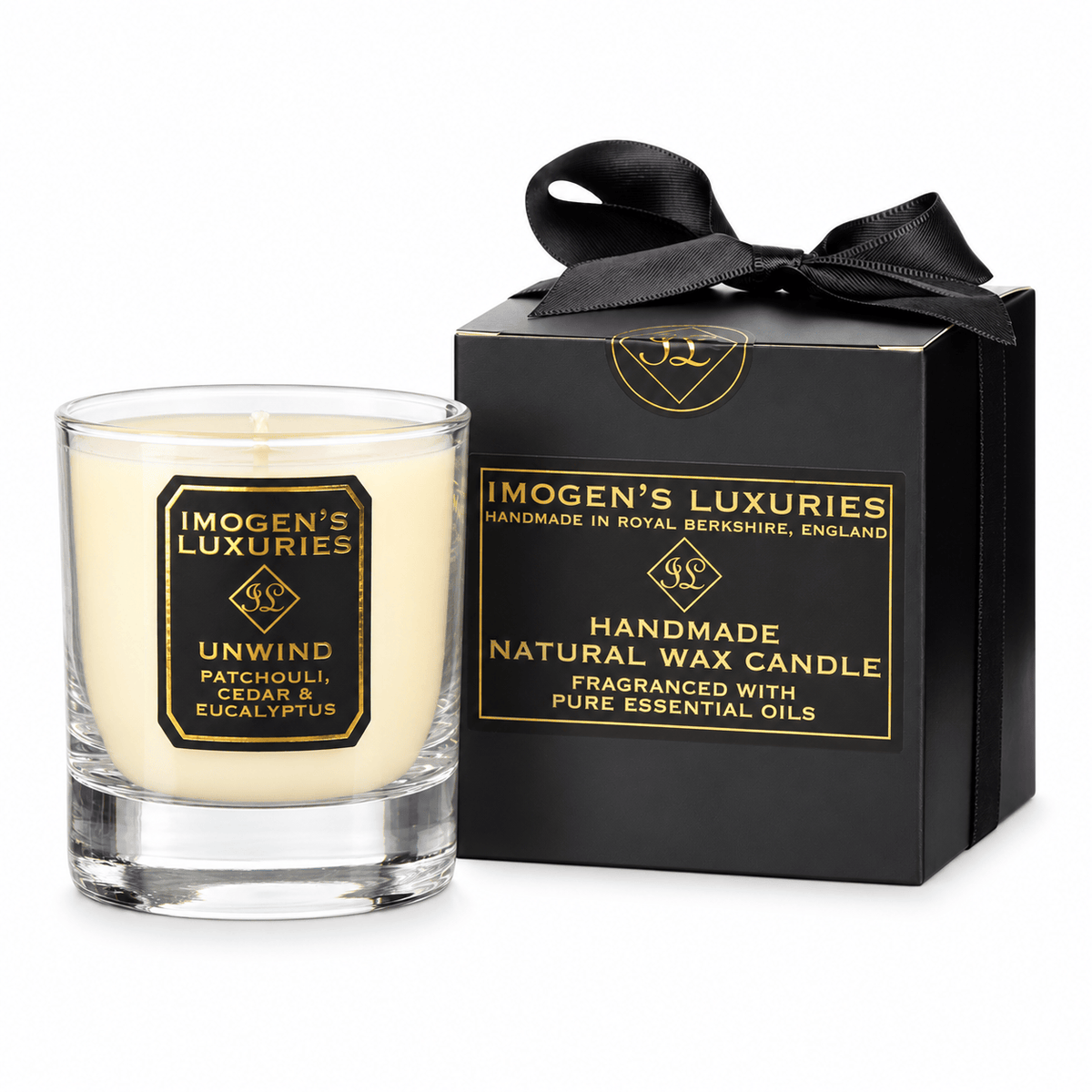 A glass container candle with natural cream coloured wax scented with Patchouli, Cedarwood & Eucalyptus Essential Oils. Candle has black and gold label and sits by a black and gold gift box with a stain bow.