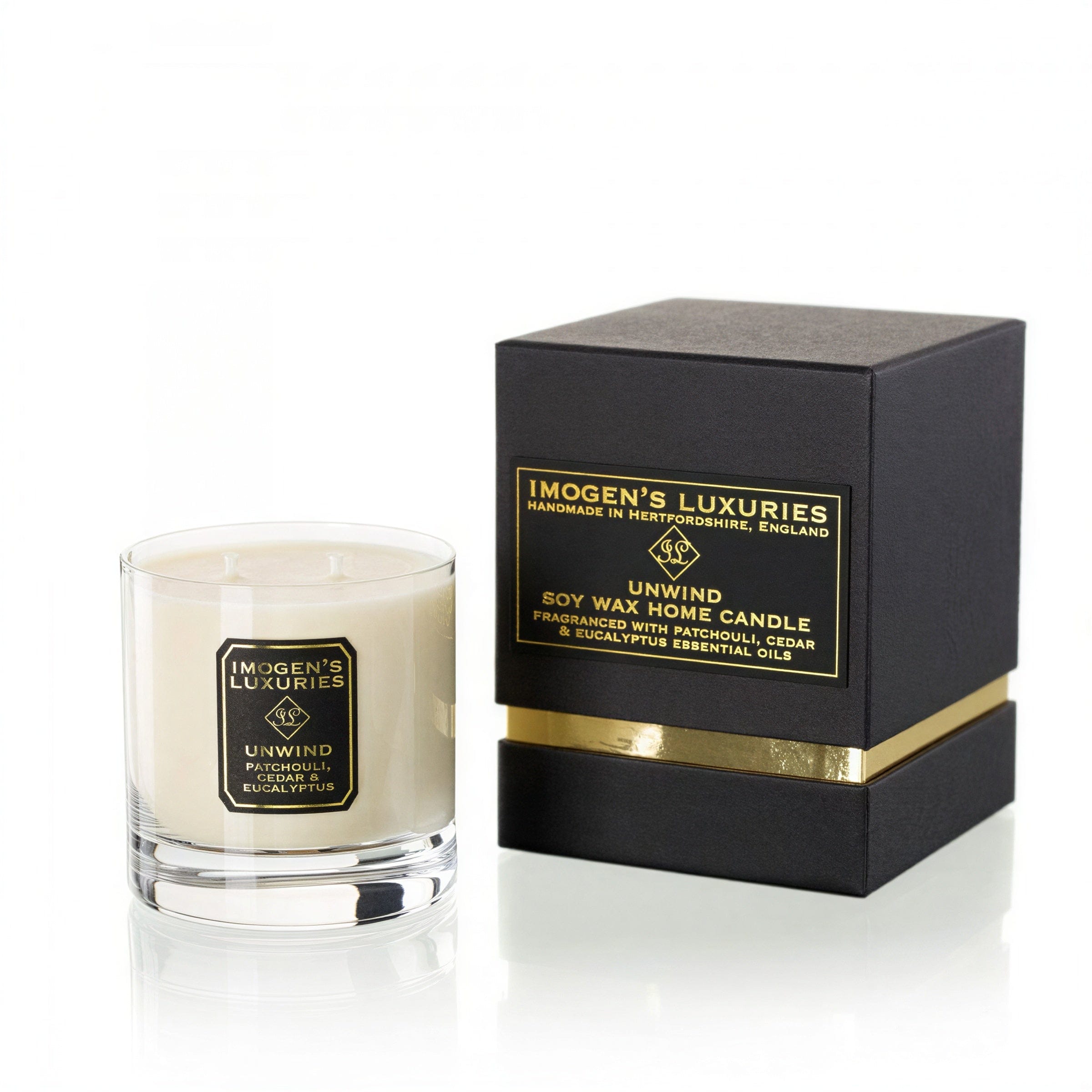 Unwind 2 wick Candle. Presented with 2 cotton wicks in a glass container next to a luxury bespoke rigid gift box. Background is white. Fragranced with Patchouli, Cedar & Eucalyptus Essential Oils. Hand-poured in Berkshire by Imogen's Luxuries